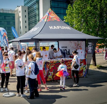 Full-surface printed promotion tent from Kafune at an event. The gazebo has corner flags. Visitors are standing with white shirts in front of the promotion tent. 