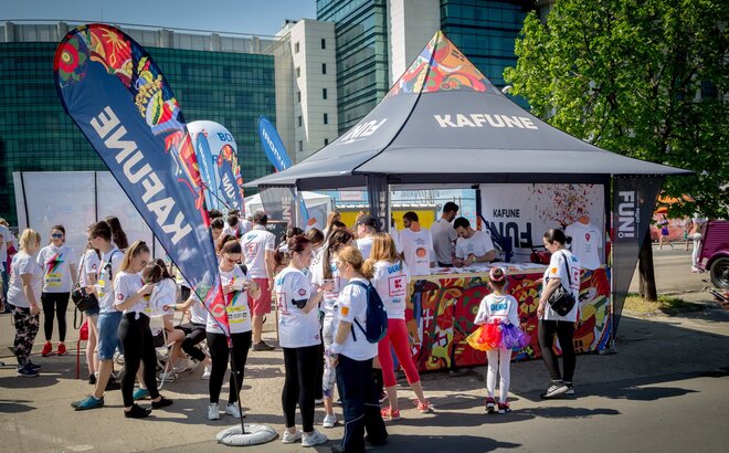 Full-surface printed promotion tent from Kafune at an event. The gazebo has corner flags. Visitors are standing with white shirts in front of the promotion tent. 