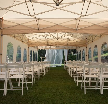 The pagoda tent in ecru used as a wedding tent. The gazebo is equipped with chairs. 