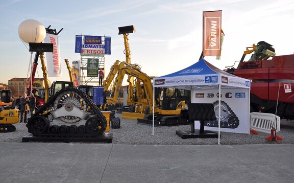 Faltpavillon von Varini auf einer Outdoor-Messe. Das Messezelt ist bedruckt. Daneben stehen Bagger und Maschinen.