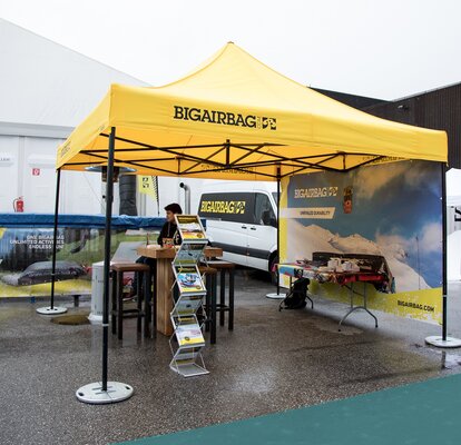 Gazebo pieghevole 3x3 m giallo personalizzato con logo stampato nero Bigairbag con struttura nera.  Gazebo ancorato al suolo con pesi in acciaio zincato per assicurare la massima stabilità. Gazebo resistente alla pioggia e al vento. 