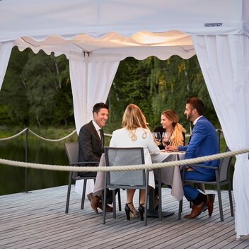 I quattro ospiti sono seduti sotto il gazebo pieghevole durante la cena. 