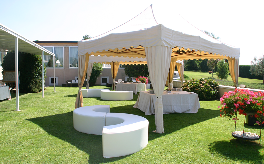 Elegant gazebo with corner curtains for an outdoor party. Underneath a beer table set is located. 