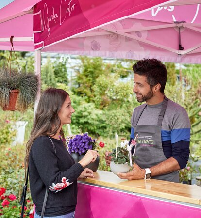 Un cliente sta parlando con un commesso della giardineria sotto ad un gazebo rosa con tettoia