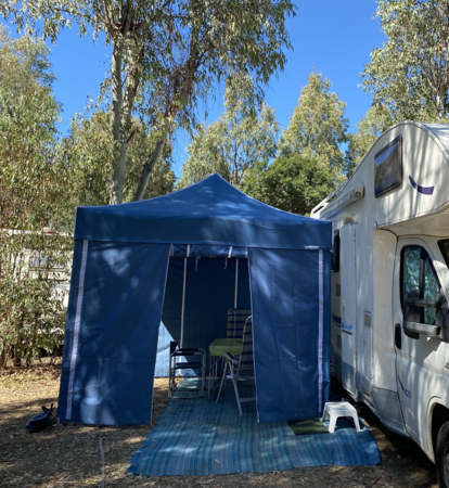 Blue camping tent with blue side walls serves as caravan awning.