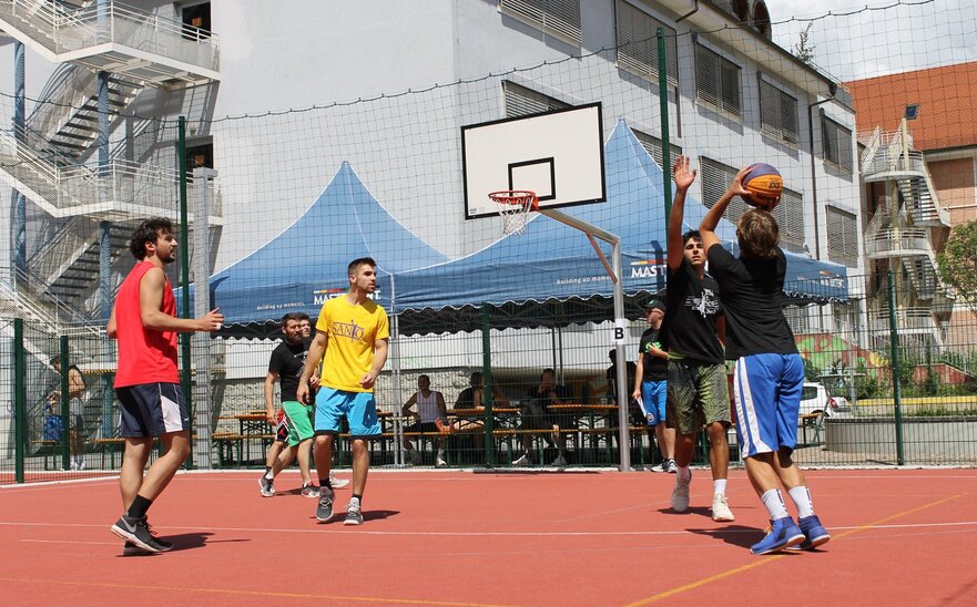 Der ragazzi giocano a basket, dietro si vedono alcuni gazebo pieghevoli MASTERTENT.