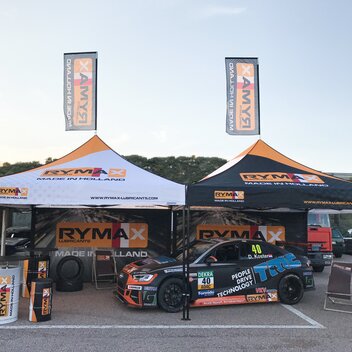 Gazebo Motorsport 3x3 m nero e bianco in sistema modulare. Grafica completamente personalizzata Rymax con pareti laterali e bandiere. Gazebo utilizzato come scuderia auto da corsa. 