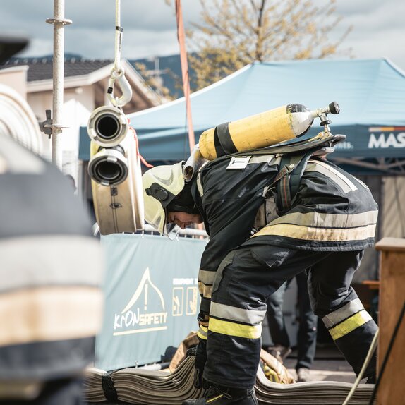 Firefighter with breathing apparatus is doing something at the ground. Behind it is a blue gazebo with the inscription MASTERTENT. 