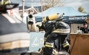 Gazebo pieghevole per intervento dei vigili del fuoco. CI sono delle attrezzature dei vigili del fuoco e un gazebo stampato MASTERTENT.