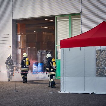 Il vigile del fuoco sta portando una vittima del incidente su una barella fuori dal capannone e la porta presso il gazebo pieghevole .