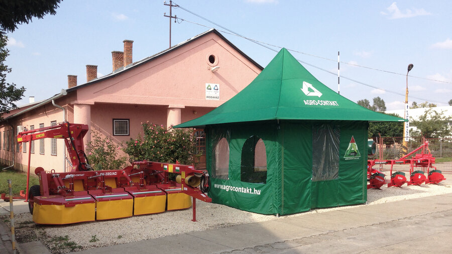 Gazebo pieghevole per agricoltura con finestre. Vicino ci sono delle macchine agricole.