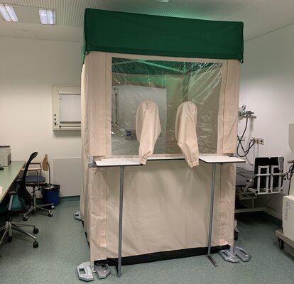 Piccolo gazebo pieghevole bianco e verde 1,5x1,5 con pareti laterali. Il gazebo viene utilizzato in uno studio medico per test clinici sul covid19