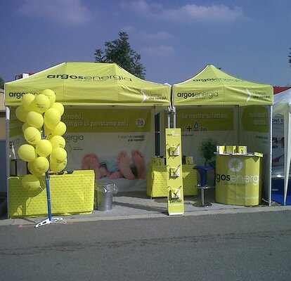 Gazebo pieghevole 3x1.5 lime con pareti laterali. Il gazebo è utilizzato per lo stand di una fiera ed è personalizzato con logo e grafiche Argosenergia