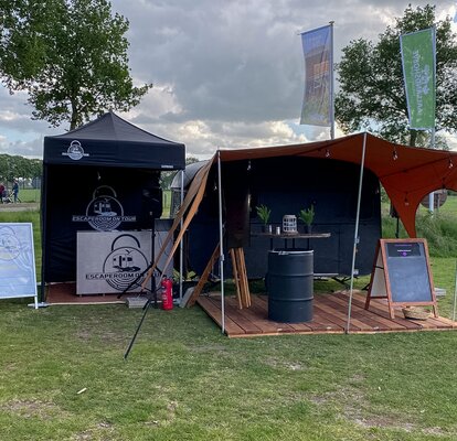 Gazebo pieghevole nero 2x2 con pareti laterali. Il gazebo pubblicitario è personalizzato con logo Escape Room on Tour e si trova in un parco 