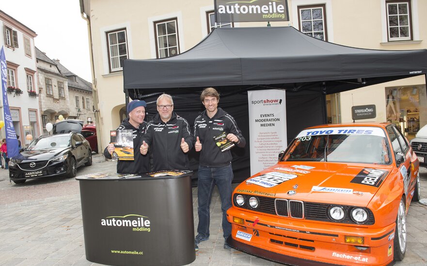 Gazebo pieghevole 4,5x3 m nero con parete laterale e banner personalizzato utilizzato per stand fiera automobilistica da Automeile möding.