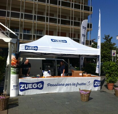 Gazebo pieghevole 4,5x3m bianco personalizzato con logo e pareti laterali a mezza altezza con bancone per stand  Zuegg.