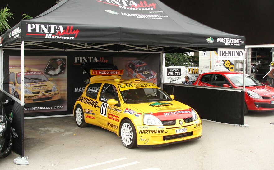 Gazebo pieghevole 4,5x3 m nero con stampa personalizzata, pareti laterali intere e a mezza altezza utilizzato da Pinta rally Motorsport come stand fiera.