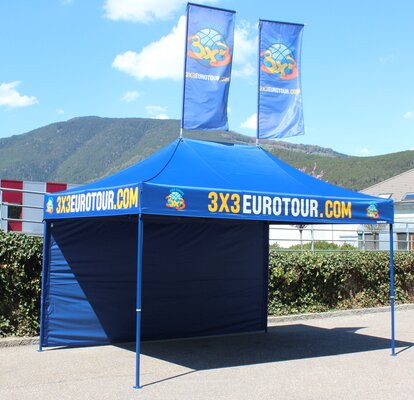 Gazebo pieghevole 4,5x3m personalizzato con logo, parete laterale e bandiere per promozione eventi di basket 3x3 Eurotour.