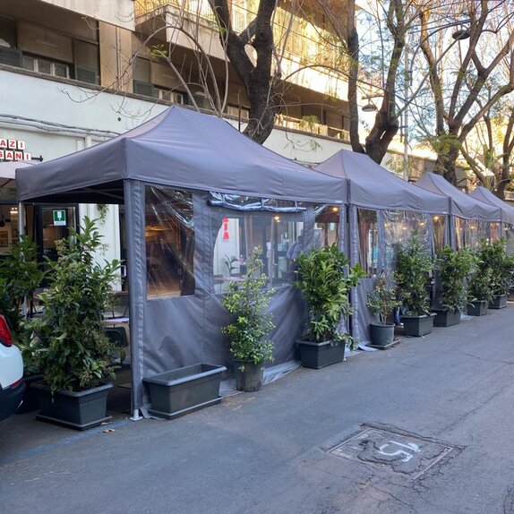 Gazebo pieghevole elegante e moderno grigio 4x2 m con pareti laterali con finestre. Fila di gazebo utilizzati nell'area esterna del locale bar ristorante Sazi e Sani per le vie della città