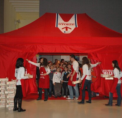 Gazebo pieghevole rosso 4x2 con pareti laterali. Il gazebo è personalizzato con logo "Il supermercato delle storie" e viene utilizzato per attività ricreative con i bambini