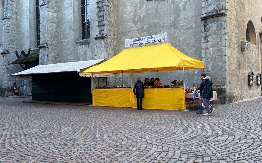 Gazebo 6x3 giallo con tettoia e parete laterale a mezza altezza con banner personalizzato Mastertent in uno scorcio di Bressanone, Italia