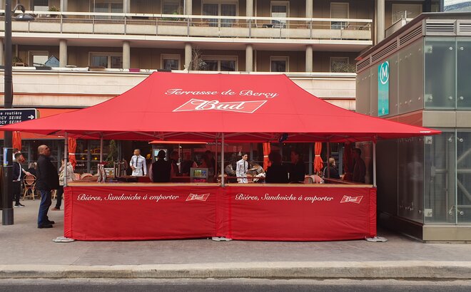 Red 6x4 folding gazebo customized with Bud logo and half-height side walls with counter for street food sale