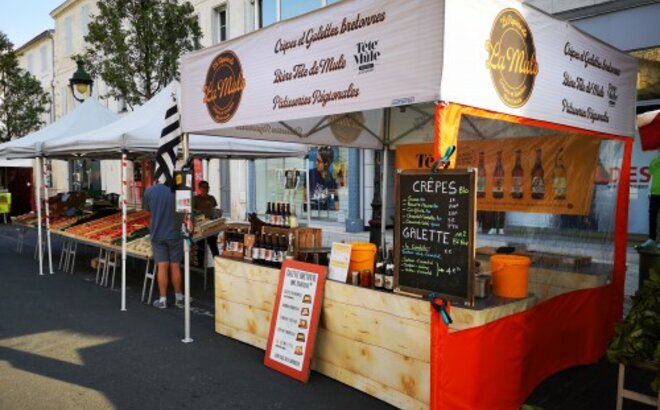 Una tenda street-food con il tetto stampato con il logo La Mule. Dotato inoltre di una parete laterale rossa con finestra panoramica. Accanto ad esso, sulla sinistra, c'è un altro stand di vendita. 