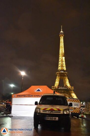 Ein Sanitätszelt steht vor dem Eiffelturm und daneben steht ein weißes Rettungsauto