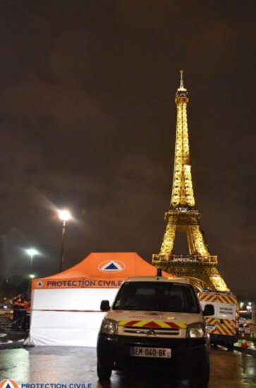 Ein Sanitätszelt steht vor dem Eiffelturm und daneben steht ein weißes Rettungsauto