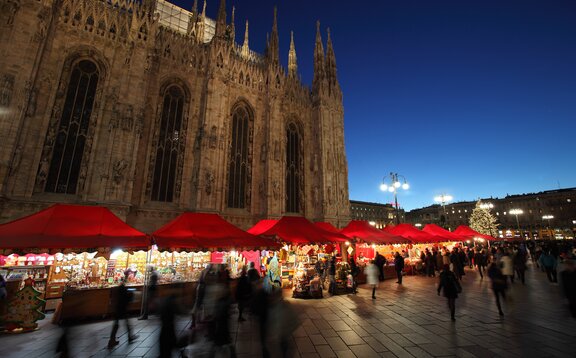 Serie di gazebo rossi di Natale 6x4m con frontalino ondulato, pareti laterali chiuse e a mezza altezza con decorazioni natalizie utilizzati ai mercatini di Natale in Piazza Duomo a Milano di sera - Mastertent