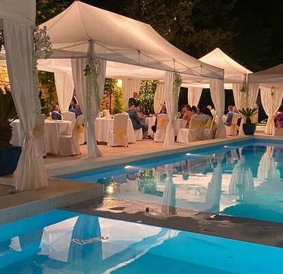 Il gazebo bianco per matrimoni è vicino alla piscina - è sera. Il gazebo è dotata di grandi illuminazioni.