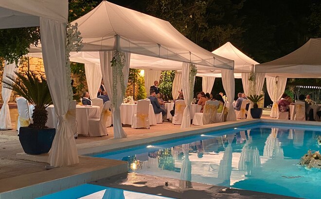 Il gazebo bianco per matrimoni è vicino alla piscina - è sera. Il gazebo è dotata di grandi illuminazioni.