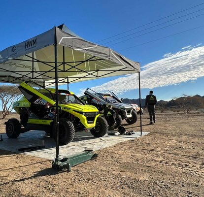 black and white racing gazebo at the Dacar Rally 2022 with two Arcane cars in the desert near the mountains