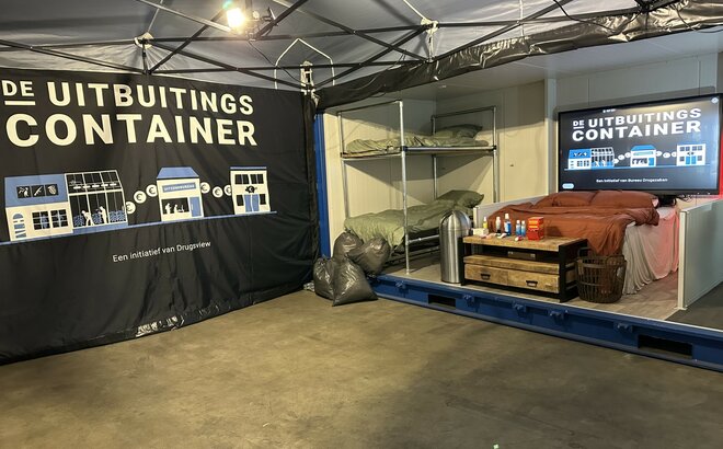 You can see the inside of a 6x4 m folding gazebo. You can see its aluminium structure, the LED spotlights, the printed side wall and the beds in the container next to it. 