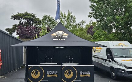 L'immagine mostra un gazebo pieghevole nero di 3x3 m con una stampa personalizzata sulle pareti laterali, sul tetto e sulla bandiera del tetto. Il gazebo è dotato anche di quattro tettoie.