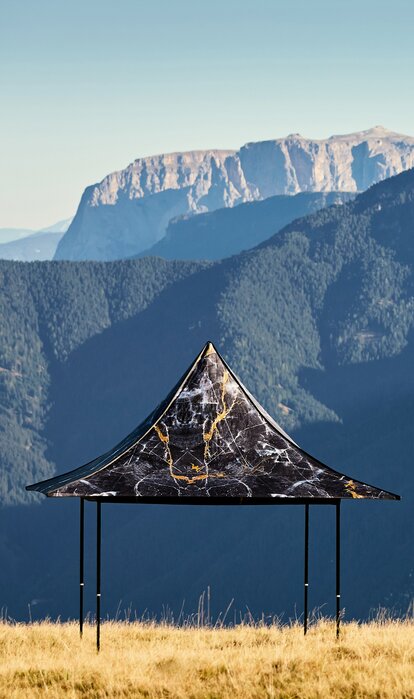 Black gazebo with 4 awnings and individual printing on the Plose mountain. In the background a mountain range can be seen. 