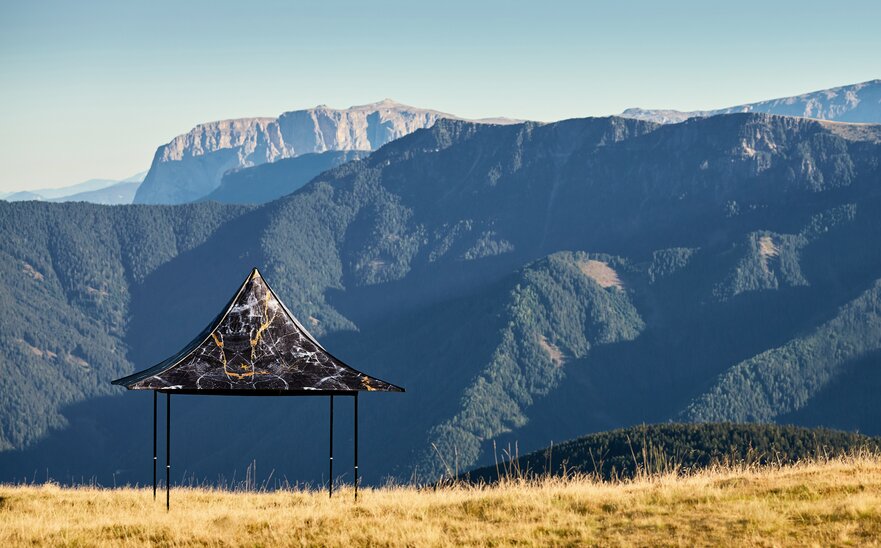 Gazebo pieghevole nero con 4 tettoie e stampa individuale sulla montagna Plose. Dietro si vede la catena montuosa.