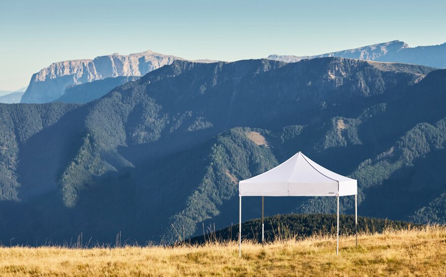 Gazebo pieghevole bianco sulla montagna Plose. Dietro si vedono le catene montuose.