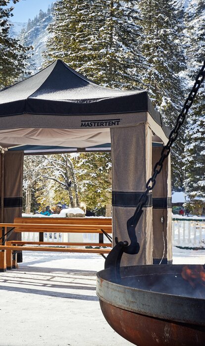 Gazebo pieghevole Mastertent invernale 3x3m in tessuto Loden verde e marrone sulla neve vicino a un falò