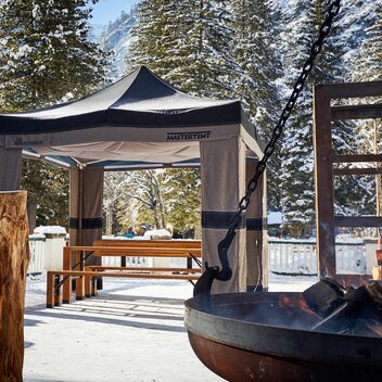 Gazebo pieghevole Mastertent invernale 3x3m in tessuto Loden verde e marrone sulla neve vicino a un falò