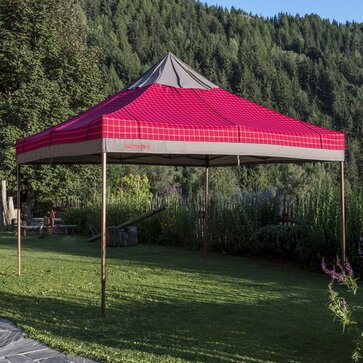 Gazebo pieghevole con copertura in tessuto Loden rosso e  grigio in giardino alpino. 