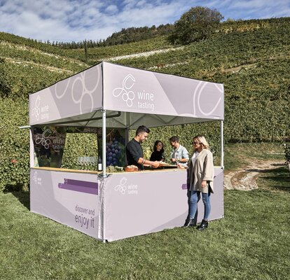 The vintner is conducting a wine tasting under a gazebo by MASTERTENT. Guests are tasting wine and cheese in front of the gazebo. 