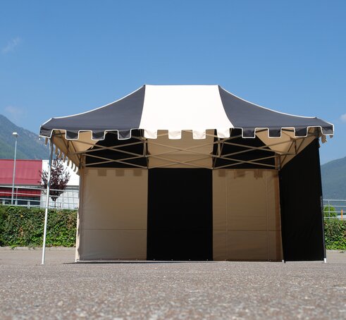 Eine eigens angefertigter Faltpavillon in den Farben schwarz und ecru steht auf einem Vorplatz. Der Faltpavillon hat eine Schlossblende.