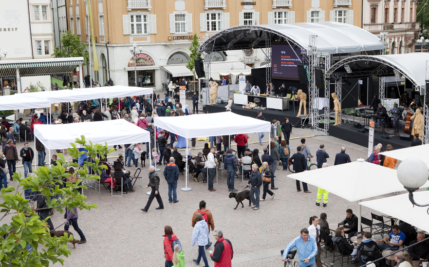 Many white custom-made gazebos with flat roofs at a festival. 