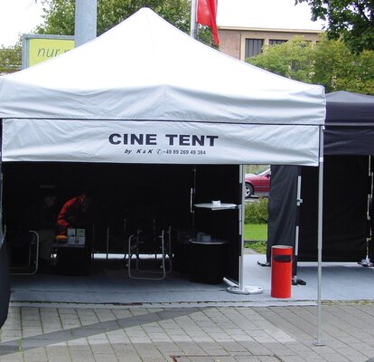 Der speziell angefertigte Faltpavillon ist mit einem abnehmbaren "CINE TENT"-bedrucktem Werbebanner ausgestattet. Dieser wird mit einem Klett wie eine Seitenwand am Dach und an den Eckstehern des Faltpavillons befestigt.