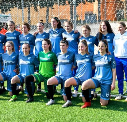 Auf einem Fußballfeld, unter einem Tor, stehen bzw. knien die Fußballspielerinnen eines Südtiroler Sportvereins.