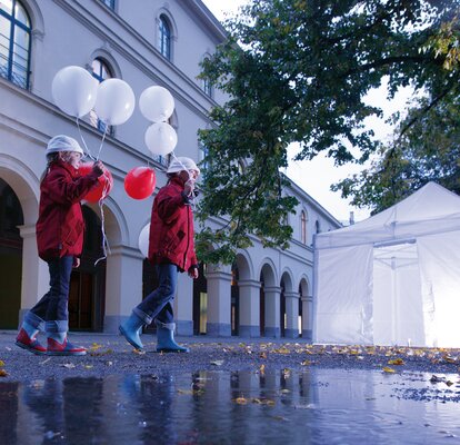 2 bambini con palloncino passano davanti ad un gazebo illuminato.