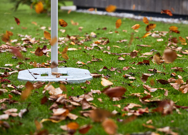 The gazebo is fastened with gazebo weights. The wind is blowing many leaves around. 