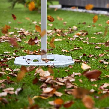 Il gazebo pieghevole è fissato con dei pesi. Il vento soffia tra le foglie.