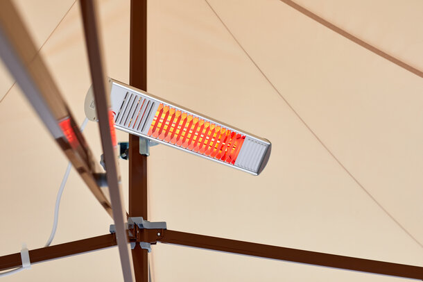 A mobile infrared heater mounted on the mast of a Mastertent canopy tent.